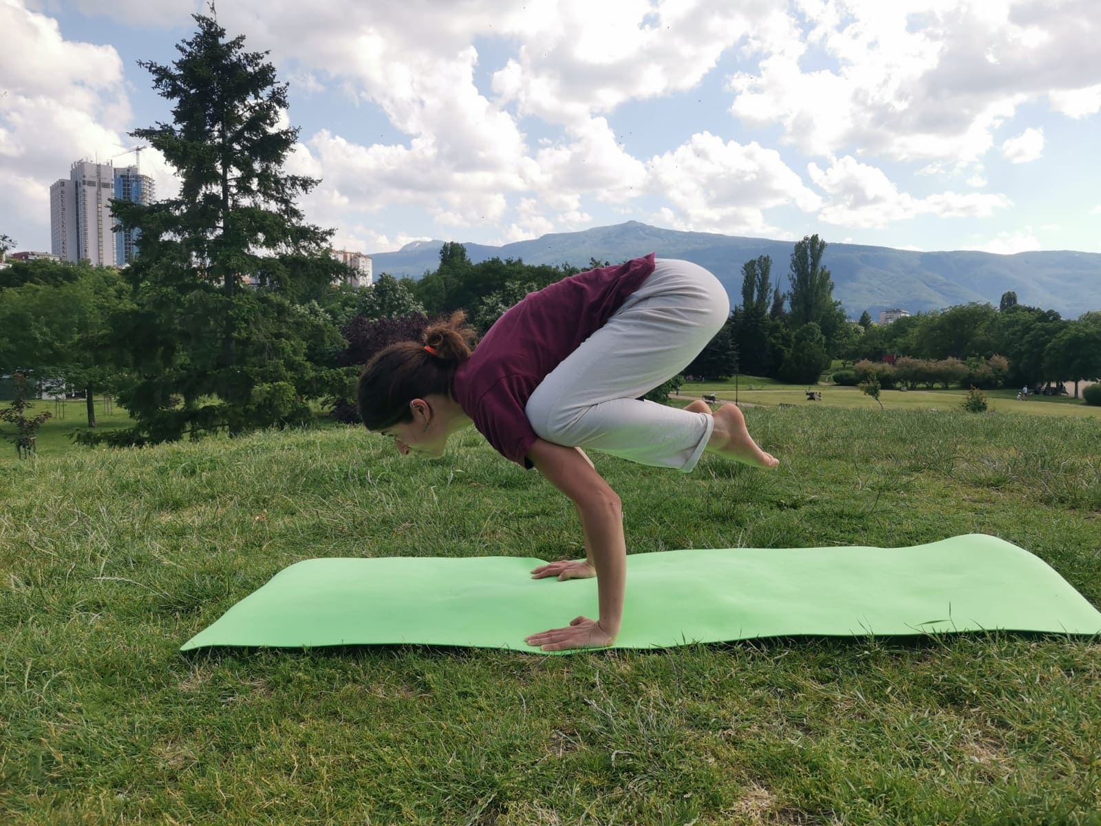 Kakasana yoga pose outdoors on a green mat